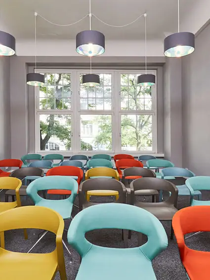 Een kamer met veel kleurrijke stoelen.