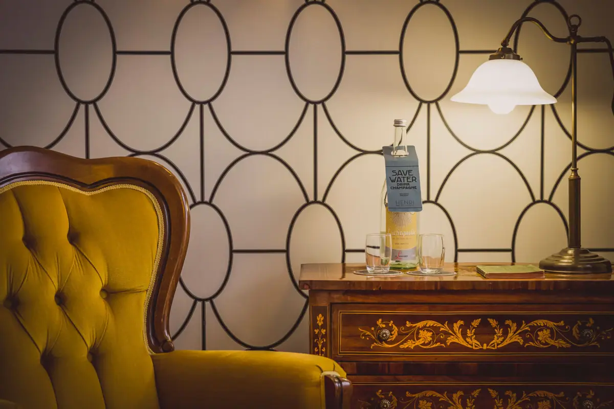 Details kamer Een stoel en een tafel met glazen en een fles erop.