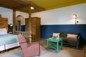 HENRI GAP-salon met balkon Een kamer met twee bedden en een groene tafel.