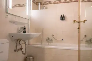 Badkamer in de kamer met balkon in het HENRI in Garmisch-Partenkirchen Een badkamer met wastafel en bad.