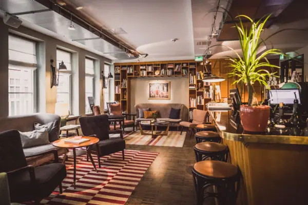 Loungegedeelte met bar, krukken, fauteuils en kleine tafeltjes. 