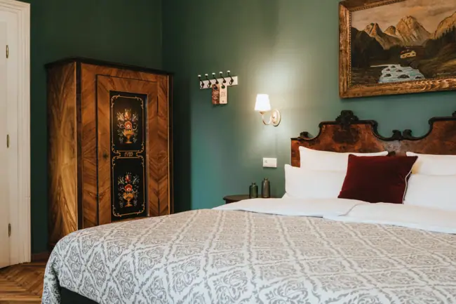 Kamers in het HENRI Hotel Kitzbühel Een bed met kussens en een kast in één kamer.