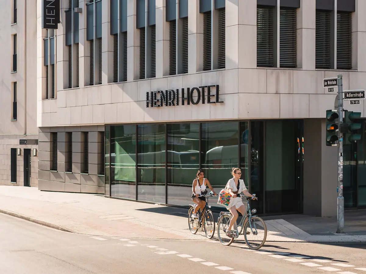 HENRI Hotel Düsseldorf Een groep mensen fietst langs een hotel.