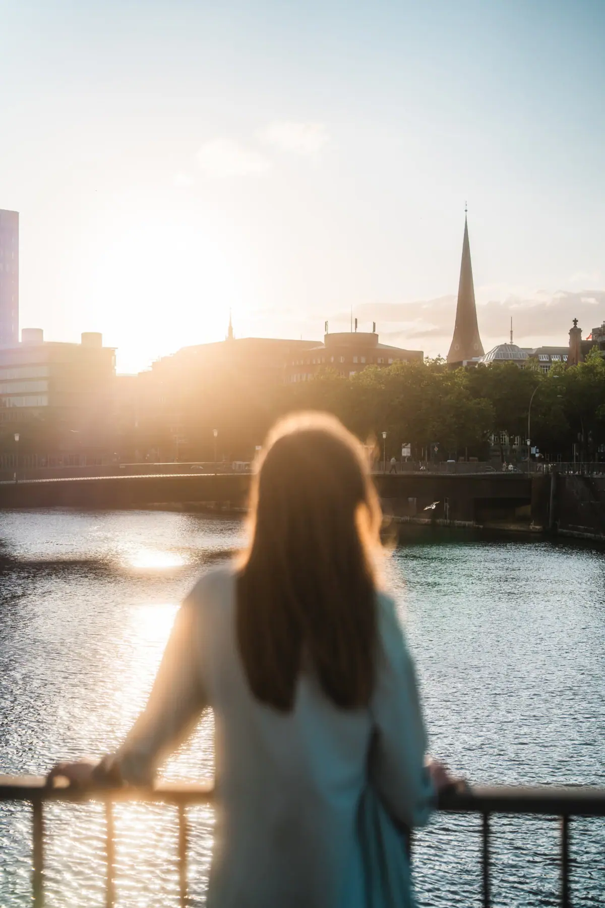 Hamburg Een vrouw staat op een brug en kijkt uit over een stad.