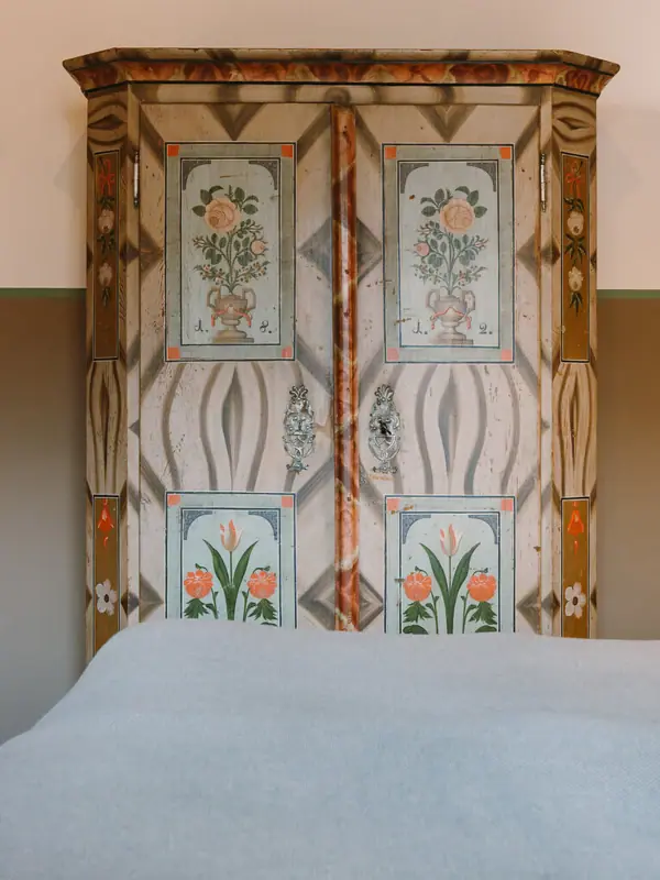 Een bed met een geschilderde kleerkast op de achtergrond.