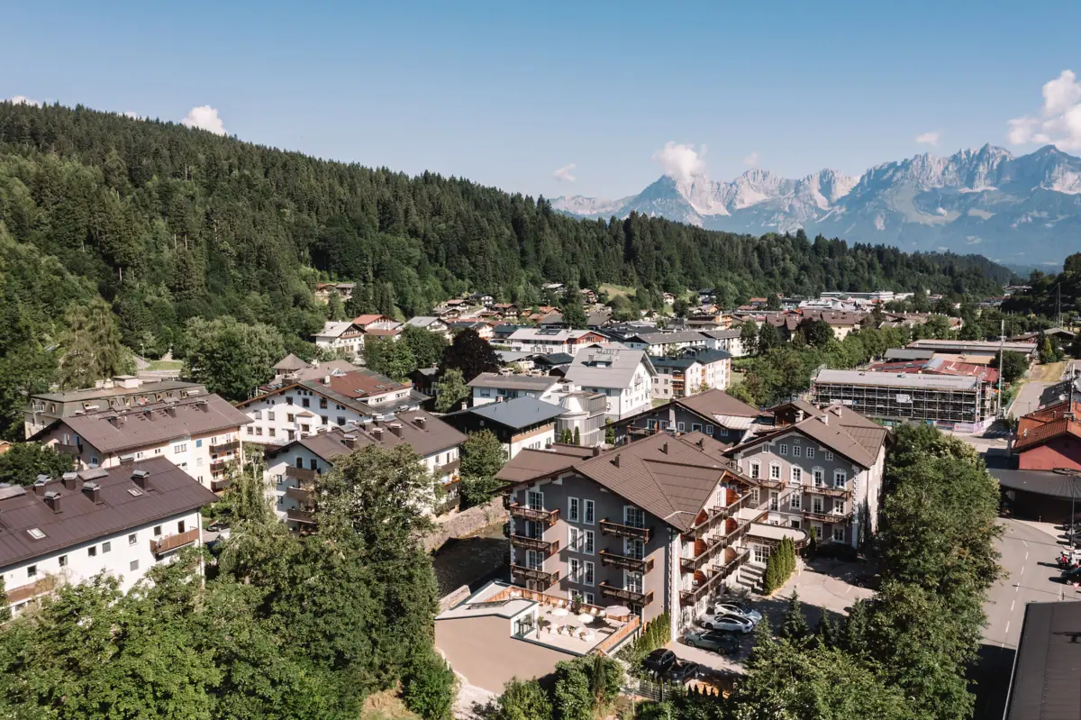 HENRI Hotel Kitzbühel Een groep gebouwen met bomen en bergen op de achtergrond.