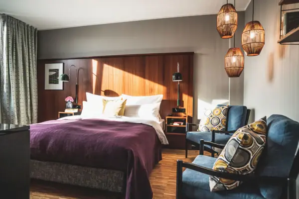 Hotelkamer HENRI Düsseldorf Een slaapkamer met een bed en stoelen.