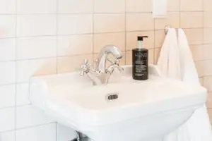 Badkamer HENRI Kitzbühel Spiegel boven een wastafel met een bloem in een vaas