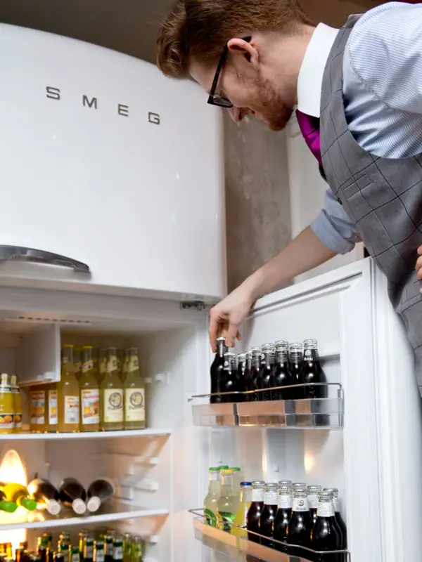 Een medewerker kijkt in de koelkast met drankjes