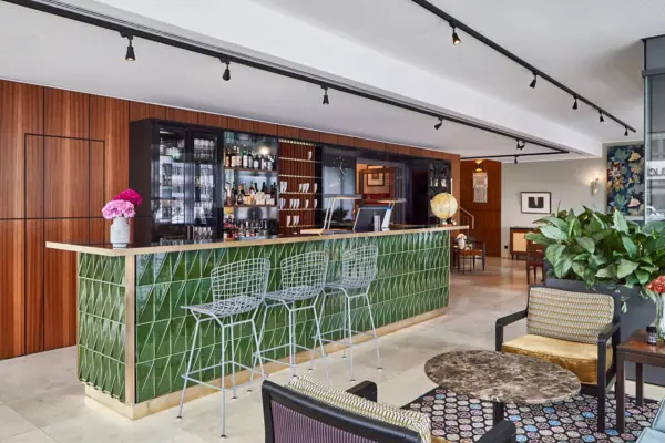 Een bar met groene tegels en stoelen.