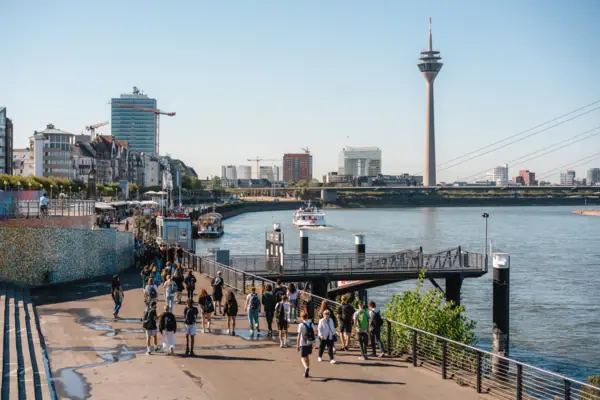 Düsseldorf Een groep mensen loopt over een pad bij een meer.