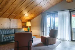 Zithoek Kamer met houten plafond, bank en fauteuils.