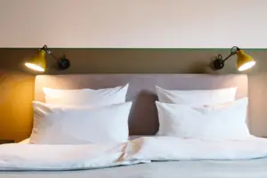 Een bed met witte kussens en een lamp in het HENRI Hotel Garmisch-Partenkirchen.