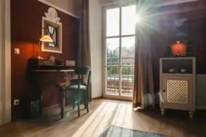 Salon Haus Kaiser HENRI Kitzbühel De Salon hotelkamer in het HENRI Hotel Kitzbühel met rode muren, een bureau en een raam.