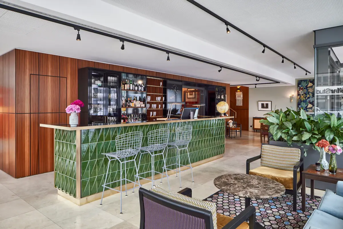 HENRI Düsseldorf Een bar met groene tegels en stoelen.