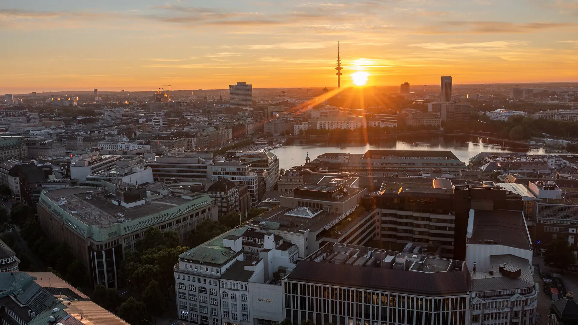 De skyline van Hamburg bij zonsondergang, met de televisietoren en de Binnenalster.