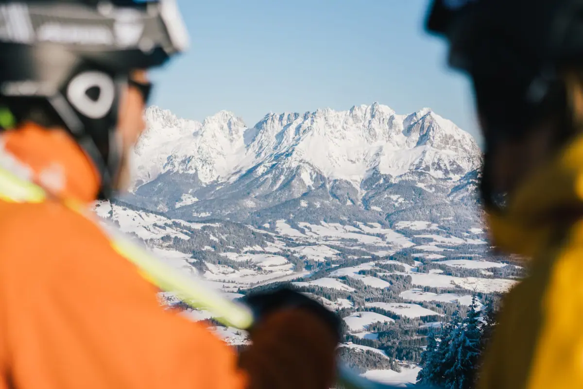 Een groep mensen op een skipiste kijkt naar een besneeuwde berg.