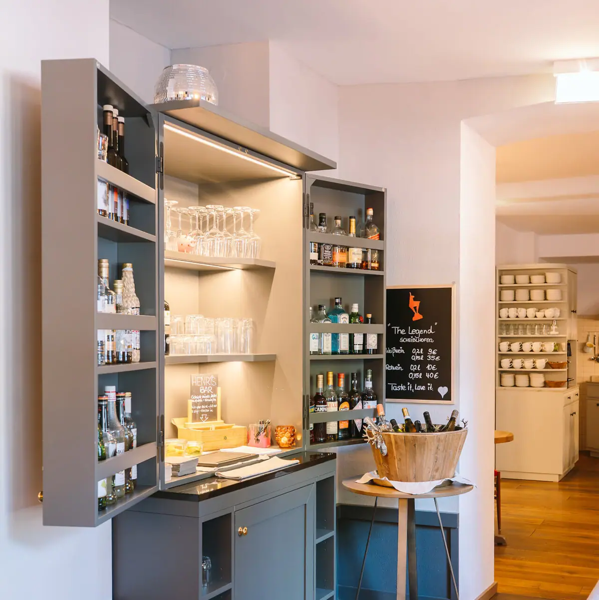 Een kamer met een kast en planken met flessen en glazen.