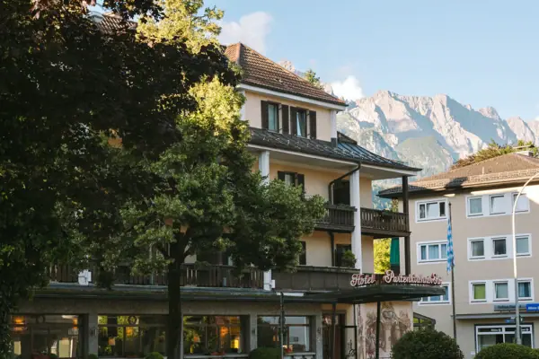 Een gebouw met bomen en bergen op de achtergrond.