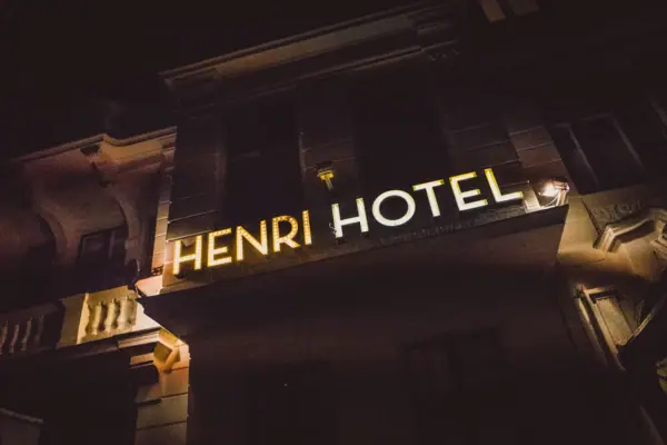 Het goudgeel oplichtende neonbord „HENRI HOTEL“ op de historische buitengevel van het hotel in Berlijn bij nacht.