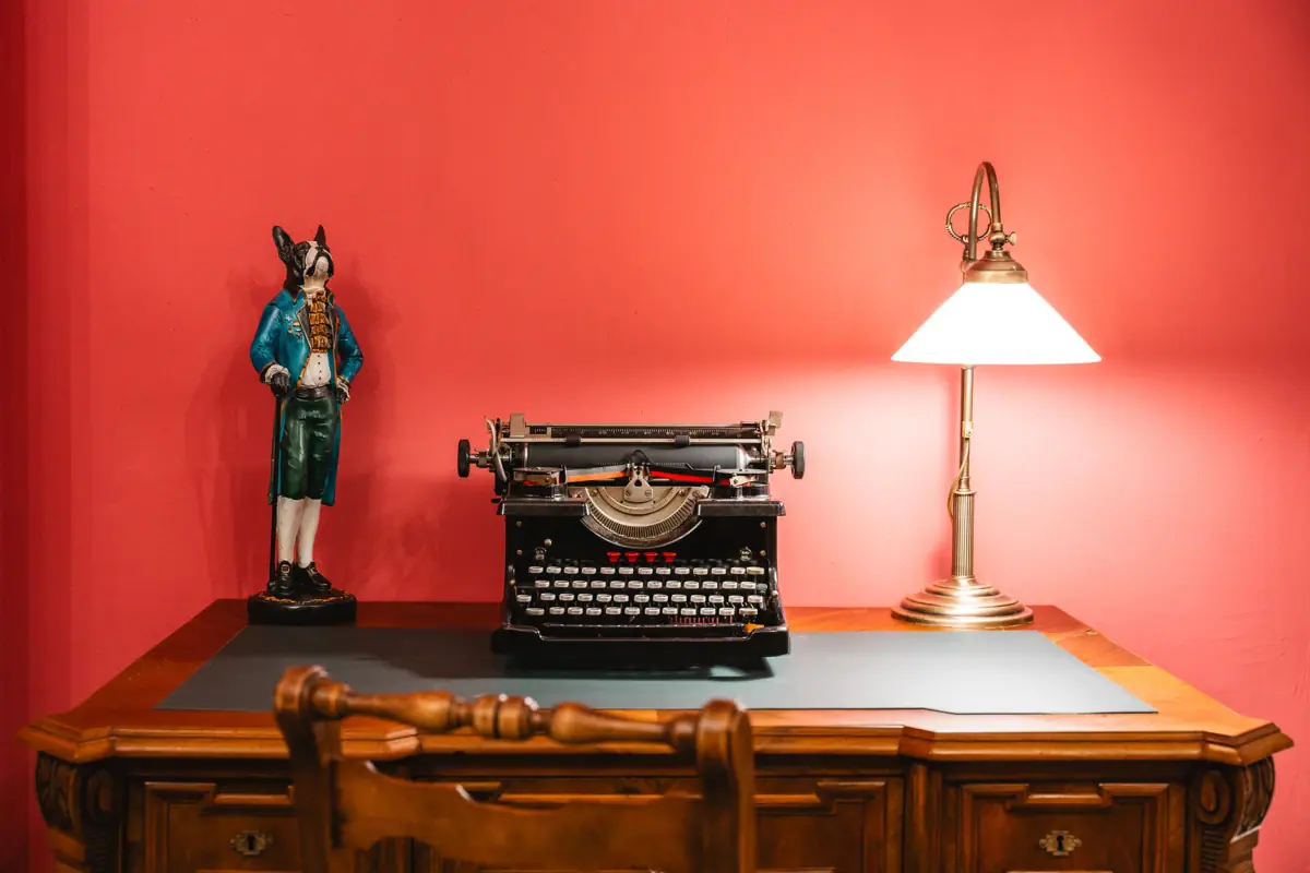 Rode salon Een bureau met een lamp en een typemachine.