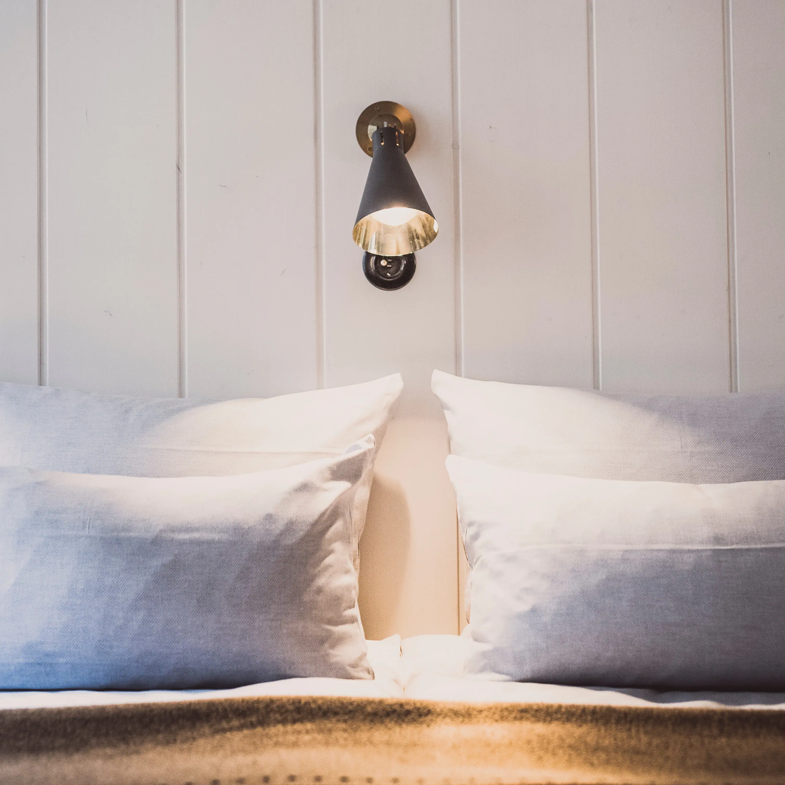 Wandlamp boven een bed met kussen