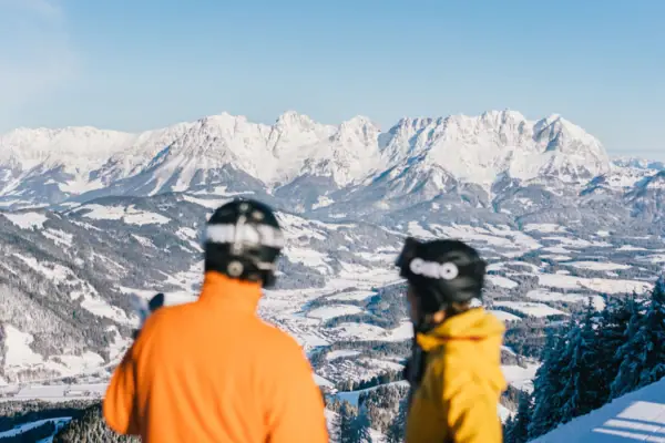 Tiroler Alpen in de sneeuw Twee mensen met helmen kijken uit over besneeuwde bergen.