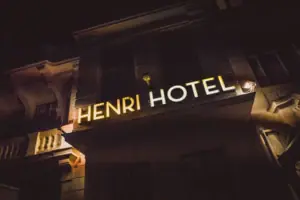 HENRI Hotel Berlijn – Gevel met lichtreclame ’s nachts Het goudgeel oplichtende neonbord „HENRI HOTEL“ op de historische buitengevel van het hotel in Berlijn bij nacht.