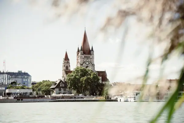 Een gebouw met een klokkentoren en bomen aan het water.