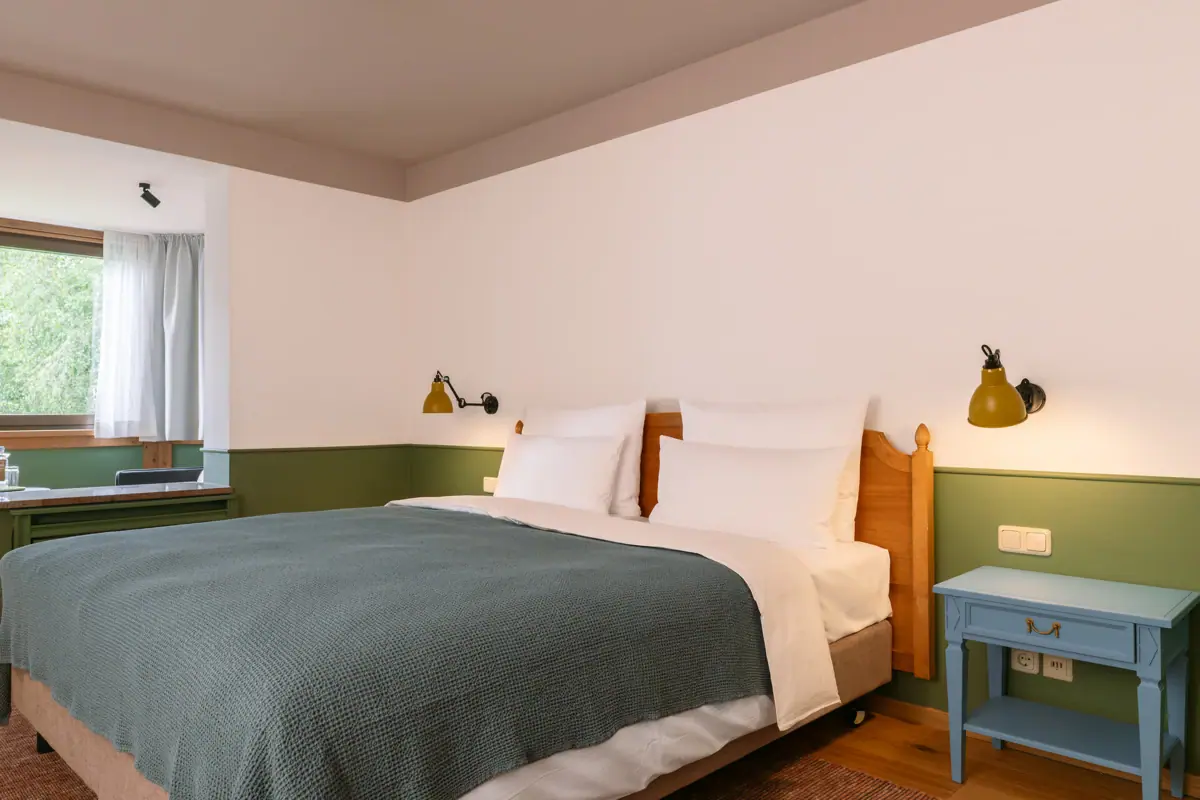 Een bed met kussens en een lamp op een nachtkastje.