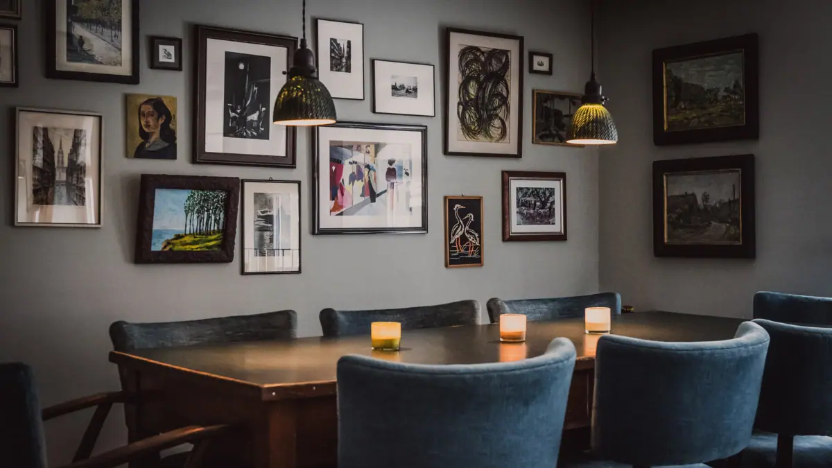 Een tafel met kaarsen en stoelen in de kantoorkeuken met foto's aan de muur.