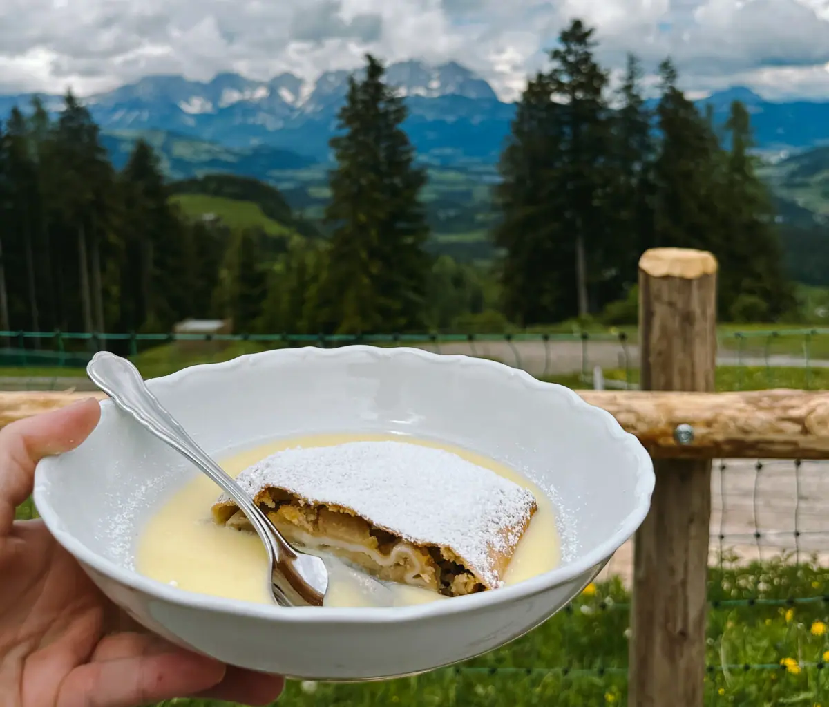 Eén hand houdt een kom met eten en een lepel vast.
