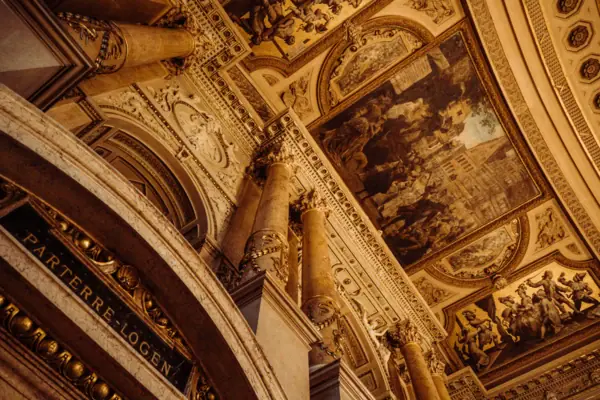 Plafond met zuilen en schilderijen, symmetrisch vormgegeven en kunstzinnig versierd.