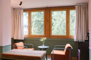 Een zithoek met twee fauteuils voor een raam in de hotelkamer Chambre in het HENRI Hotel Garmisch-Partenkirchen.