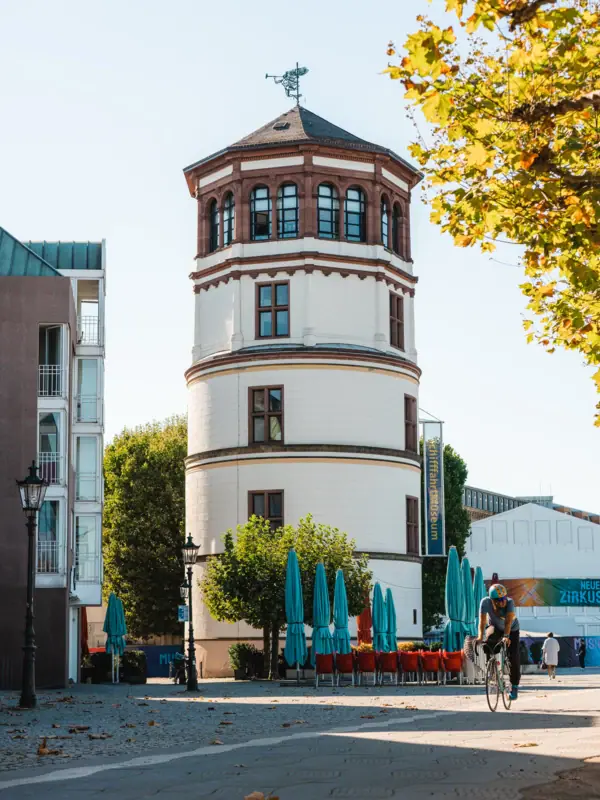 De kasteeltoren van Düsseldorf Een man fietst langs een rond gebouw.
