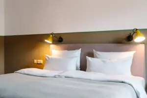 Een bed met witte kussens en een lamp.