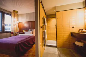 De S-Studio in het HENRI Hotel Düsseldorf heeft een bed en een aangrenzende badkamer met wastafel en douche.