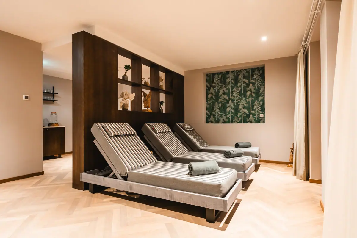 Ontspanningsruimte in de HENRI Spa Een kamer met stoelen en een muur.