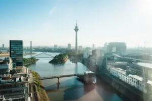 Düsseldorf Een rivier met een brug en een stad met een toren.