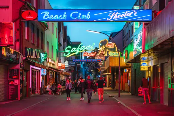 HENRI HH Reeperbahn Een groep mensen loopt door een straat met verlichte neonreclames.