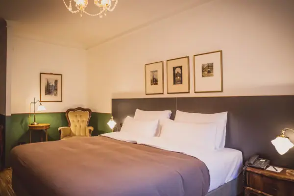 Kamer Een bed met een kroonluchter en foto's aan de muur.