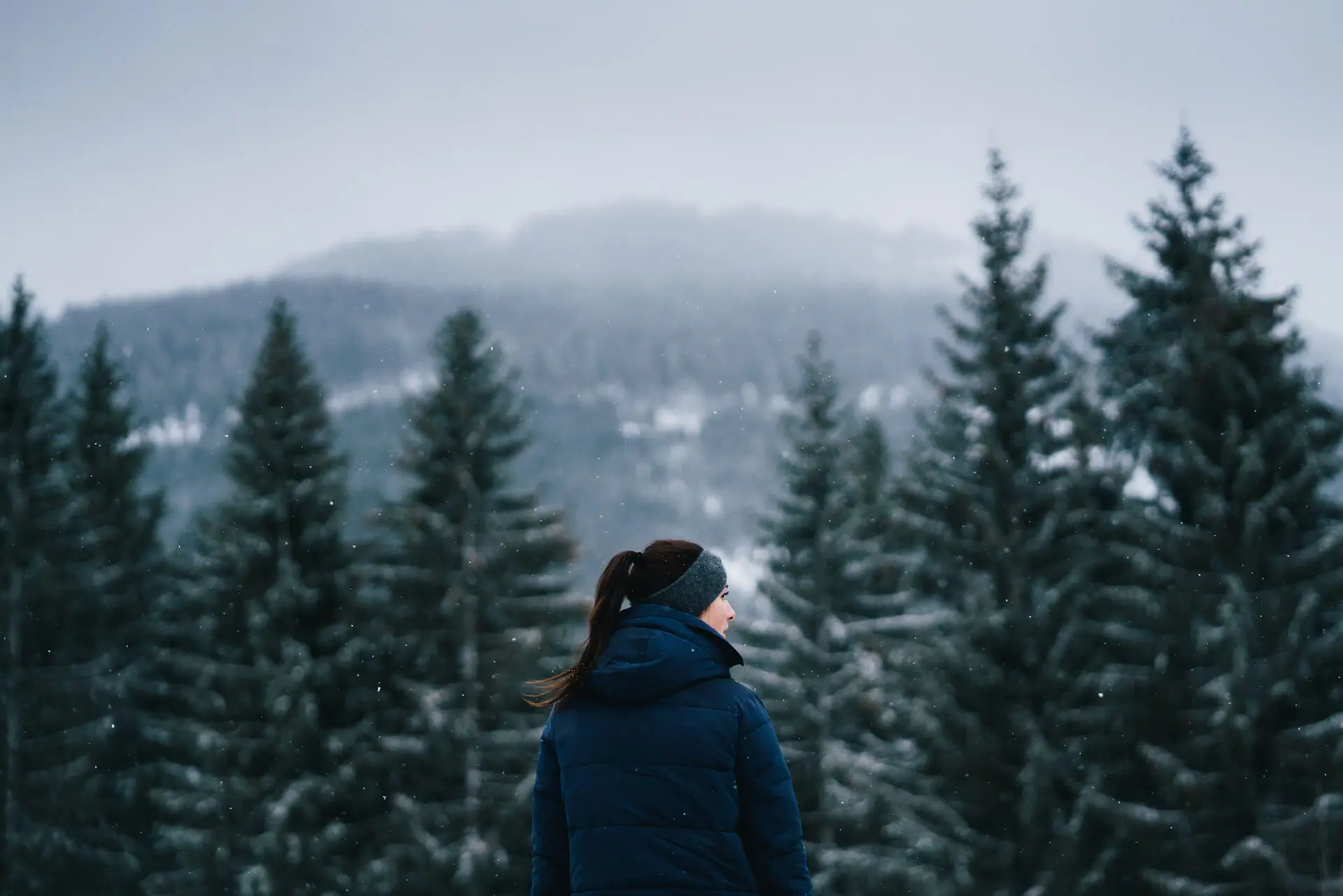 Kitzbüheler Alpen Een vrouw staat buiten voor met sneeuw bedekte bomen.