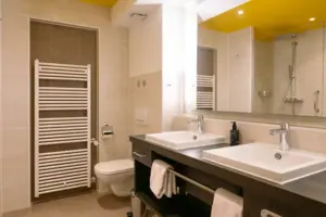 Badkamer in het HENRI in Garmisch-Partenkirchen Badkamer met een geel plafond, wastafel en kranen.