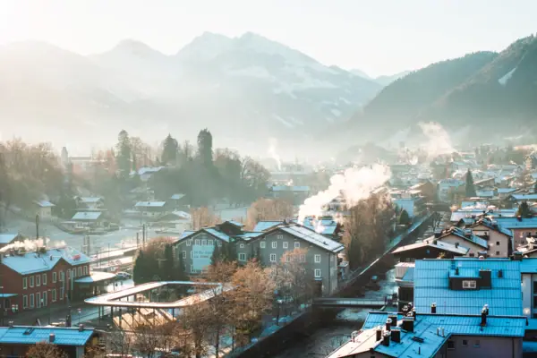 Met sneeuw bedekte daken van een stad met bergen op de achtergrond.