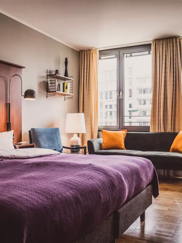 Slaapkamer met paars bed en bank.