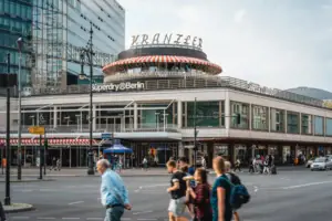 Berlin Sightseeing Café Kranzler, Kurfürstendamm De opvallende rotonde van Café Kranzler aan de Kurfürstendamm in Berlijn, met voorbijgangers op de voorgrond en de moderne architectuur van City-West.