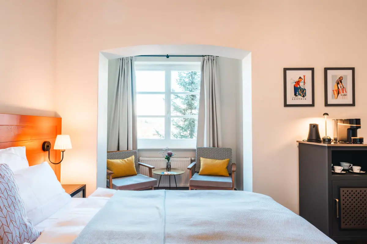 Een slaapkamer met een bed, stoelen en kussens.