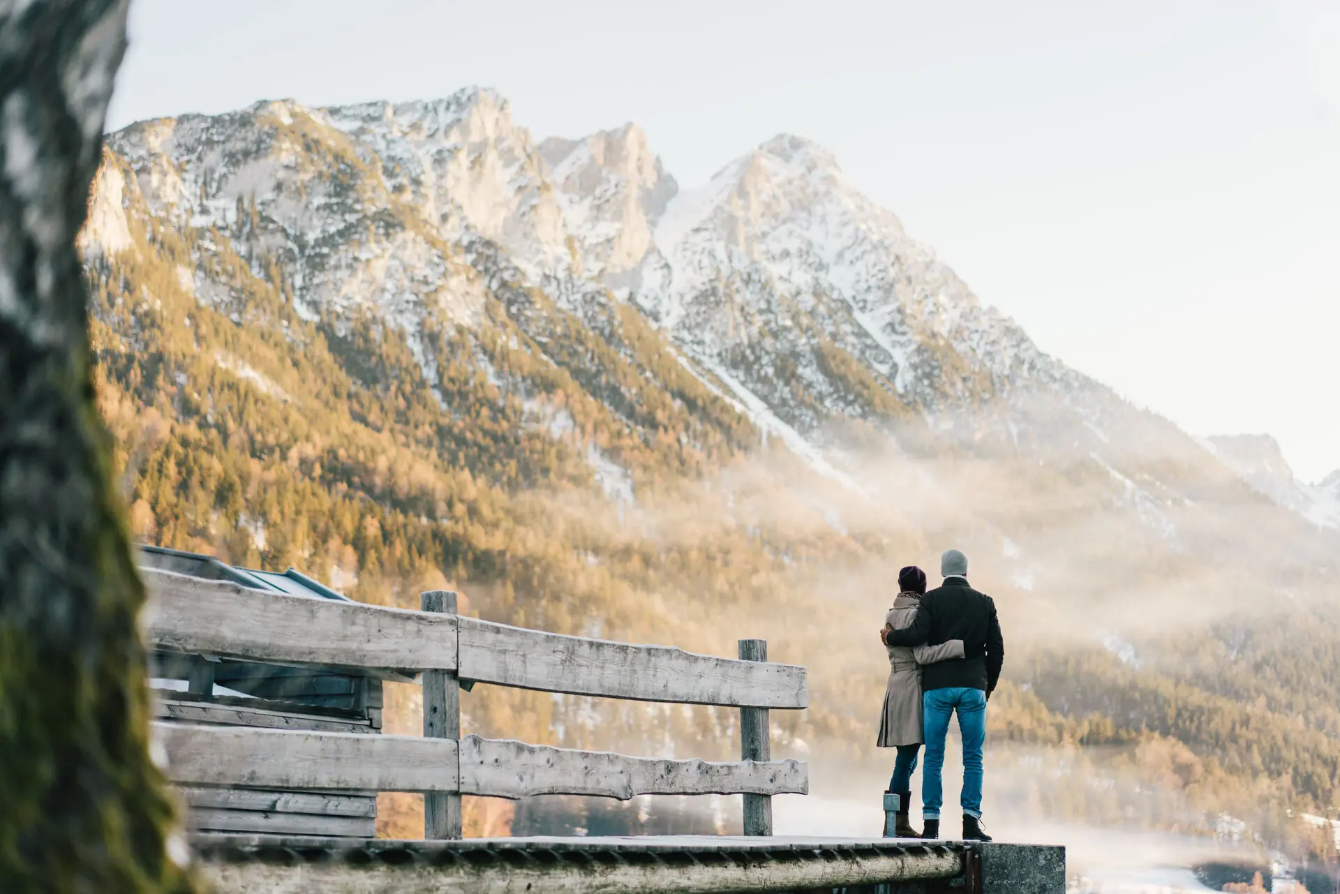 Kitzbüheler Alpen Een man en een vrouw staan op een steiger met uitzicht op een bergketen.