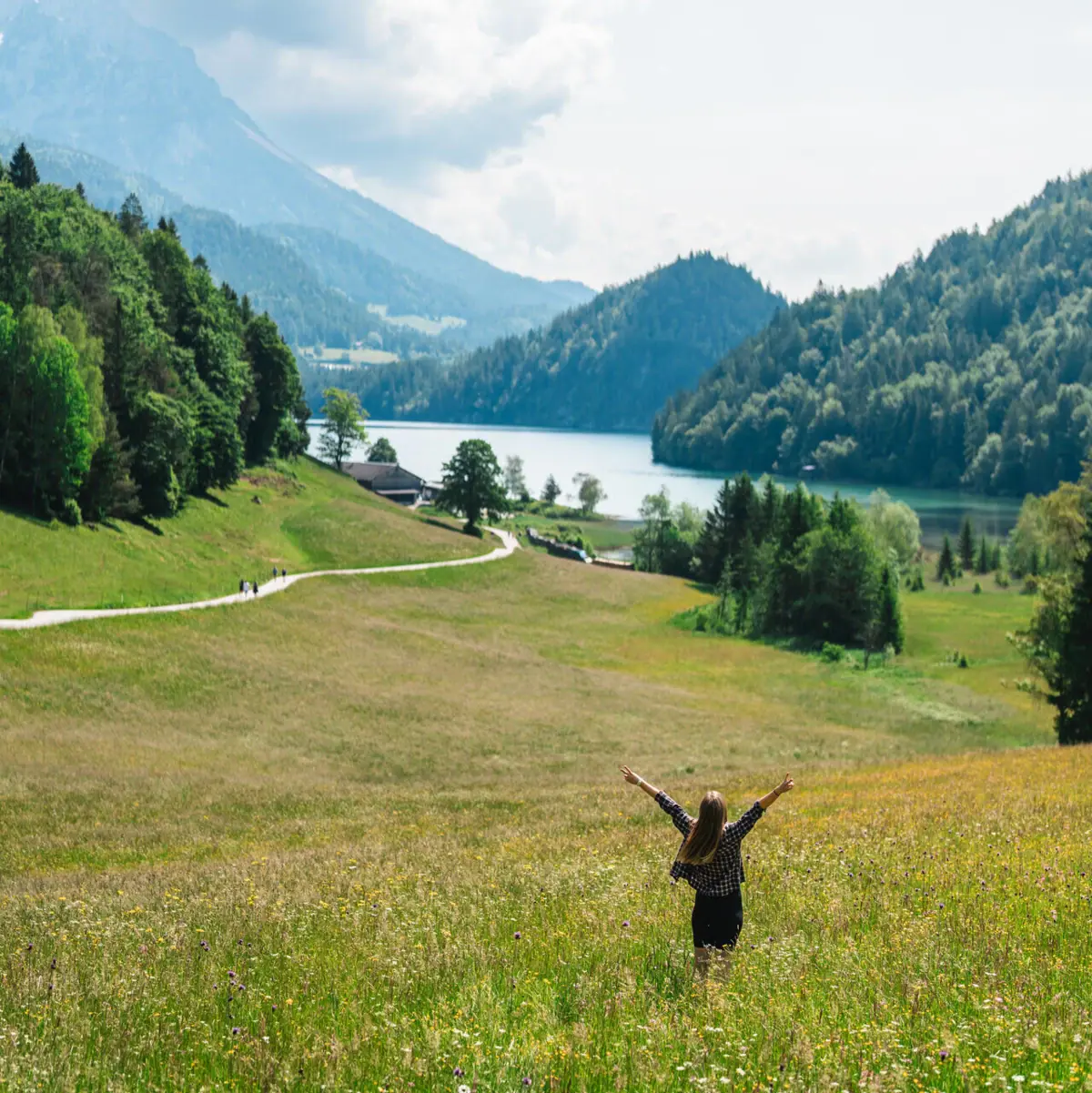 Kitzbüheler Alpen Een vrouw staat in een veld met haar armen omhoog.