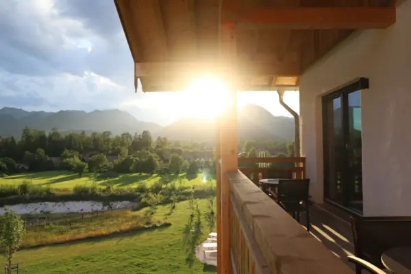 aja Hotel Ruhpolding De zon schijnt door de bomen op een verandabalkon bij aja Riuhpolding.